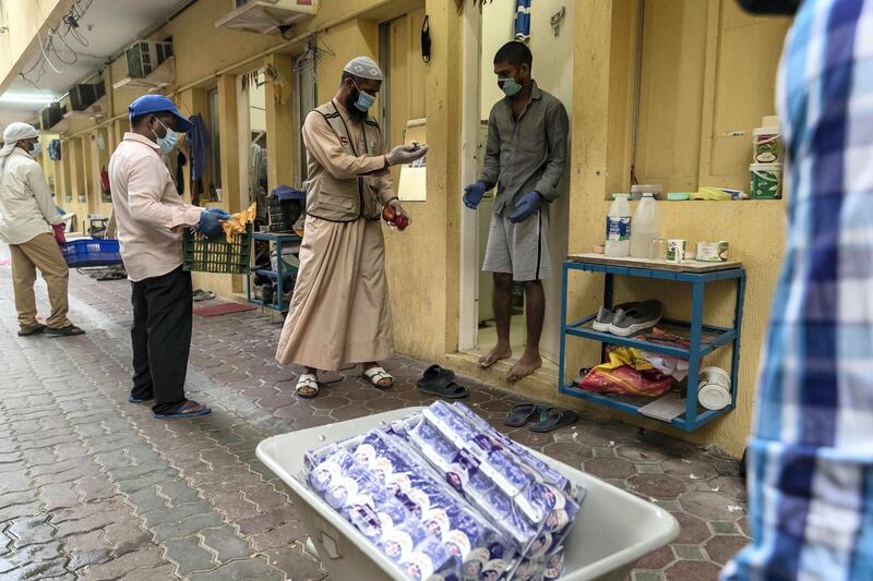 DUBAI, UNITED ARAB EMIRATES. 27 APRIL 2020. Dar Al Ber Iftar meals are handed out as part of their charity work at labour camps in Al Qouz 1. Keeping a watchfull eye is Dubai Police officers from the Bur Dubai Police Station monitoring body temperature with the new thermal helmet camera. (Photo: Antonie Robertson/The National) Journalist: None. Section: National.