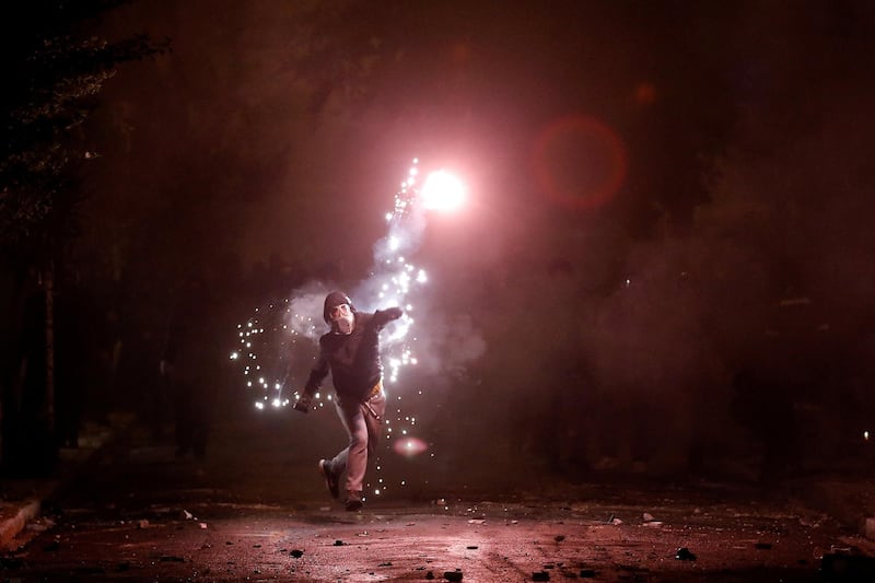 A hooded protester throws a flare during clashes following a rally marking the 44th anniversary of a 1973 student uprising against the military dictatorship that was ruling Greece, in Athens, Greece. Alkis Konstantinidis / Reuters