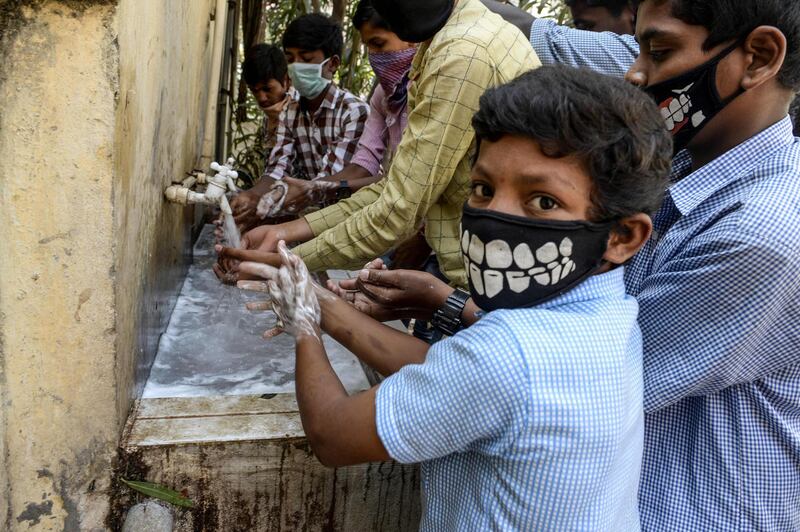 Students wearing facemasks wash their hands before attending a class in Secunderabad, India.  AFP