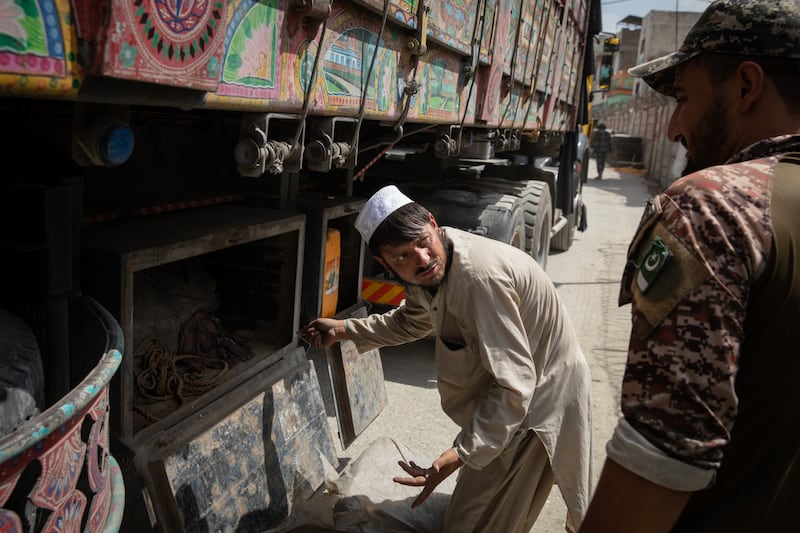 The lorry drivers are ordered down by the Pakistani border guards and made to unlock any small containers or boxes.
