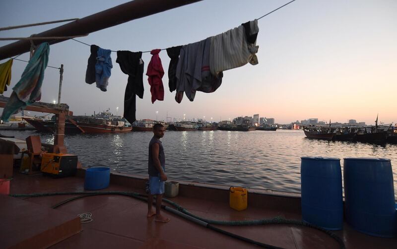 A man stands under hanging laundry in front of boats at Ras Al Khor in Dubai.  AFP