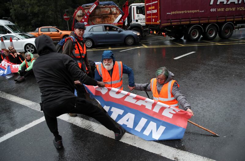 A member of the public pulls a banner away from protesters as Insulate Britain activists block a motorway junction near Heathrow Airport. Reuters