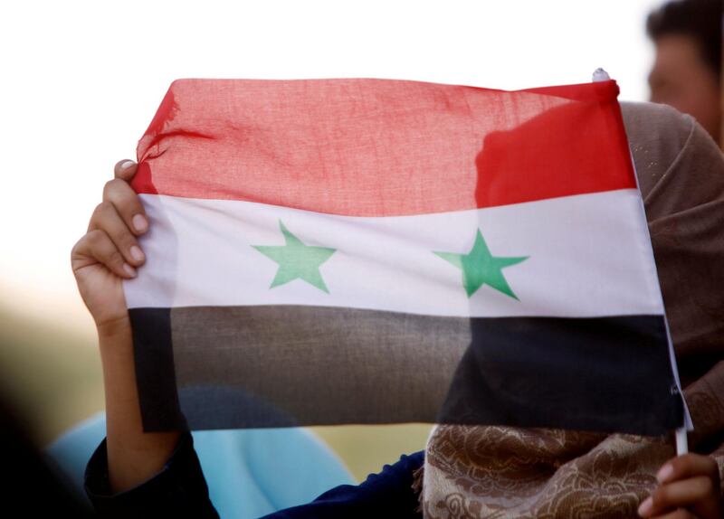 FILE PHOTO: A woman holds a Syrian flag in Deraa, Syria, July 4, 2018. REUTERS/Omar Sanadiki/File Photo