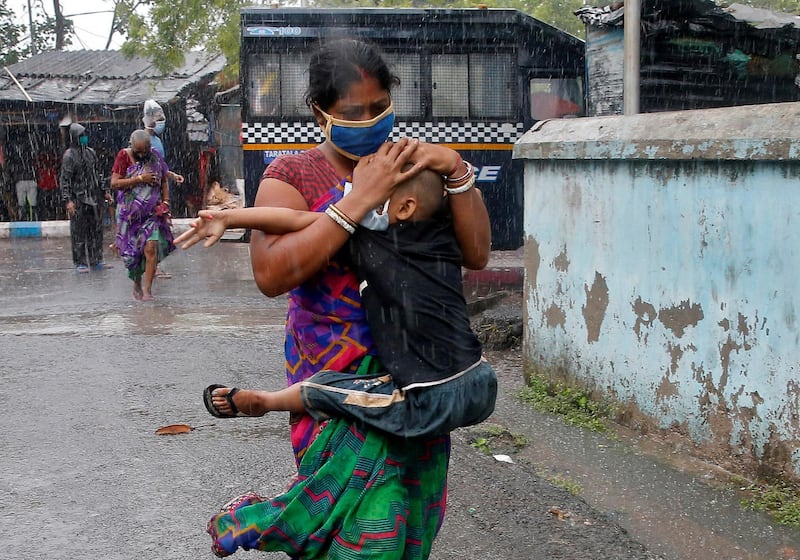 A woman carries her son as she tries to protect him from heavy rain while they rush to a safer place, following their transfer from a slum area before Cyclone Amphan makes its landfall, in Kolkata, India. Reuters