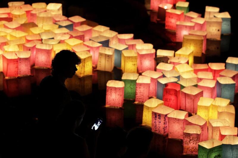 People watch floating paper lanterns on the Motoyasu River at Hiroshima Peace Memorial Park in Hiroshima, western Japan. Kiyoshi Ota / EPA