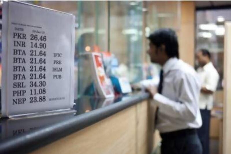 Customers send remittances to their home countries at an exchange in Deira, Dubai. With more than 130 exchange houses in the UAE, competition is intense. Razan Alzayani / The National