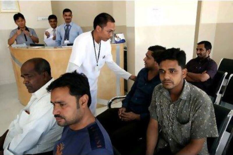 A doctor talks to labourers waiting to be seen at the Lifeline Hospital in Musaffah. Abu Dhabi's health insurance system covers people in private and in public hospitals. Stephen Lock / The National