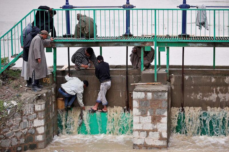 People try to stop water flowing through the gate of a flood channel after incessant rains in Srinagar, the largest city in the Indian-administered state of Jammu and Kashmir. Danish Ismail / Reuters / April 7, 2017