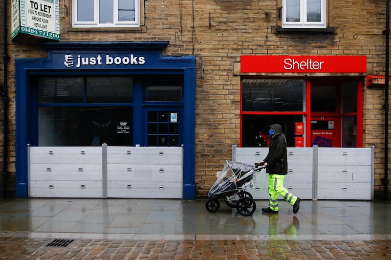A pedestrian in Hebden Bridge pushes a stroller past shops prepared for flooding brought by Storm Christoph. Reuters
