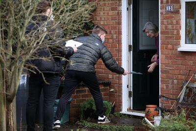 Volunteers handle out the COVID-19 home test kit to a resident in Goldsworth and St Johns, amid the outbreak of coronavirus (COVID-19) in Woking, Britain, February 2, 2021. REUTERS/Hannah McKay