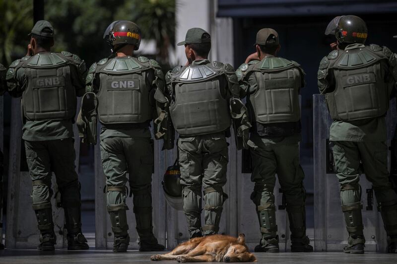 epaselect epa07573686 A dog rests behind National Bolivarian Guard (GNB) agents as they watch the surroundings of the National Assembly (NA), in Caracas, Venezuela, 15 May 2019. The Venezuelan Parliament held a session, which had to be postponed yesterday, amid tension due to a large police presence, which did not allow the press into the chamber.  EPA/Miguel Gutierrez