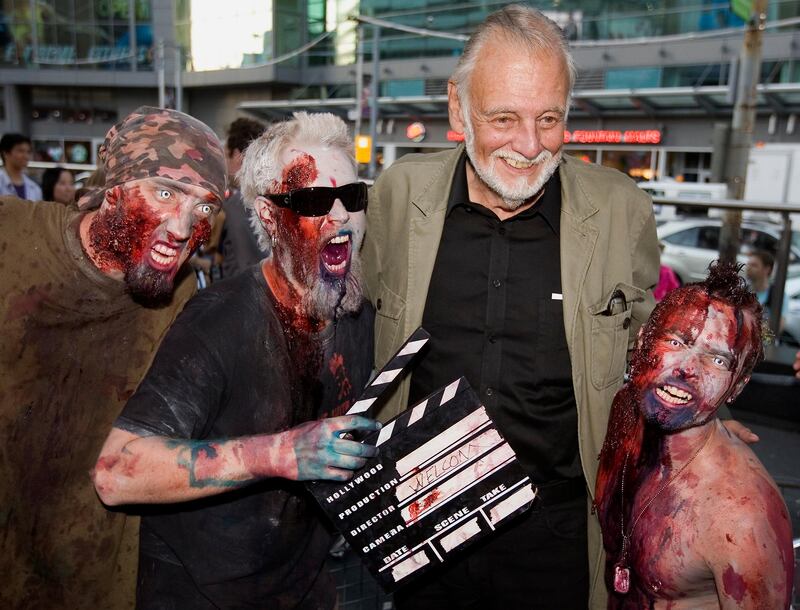 FILE - In this Sept. 12, 2009, file photo, director George Romero poses with some fans dressed as zombies after accepting a special award during the Toronto International Film Festival in Toronto. Romero, whose classic "Night of the Living Dead" and other horror films turned zombie movies into social commentaries and who saw his flesh-devouring undead spawn countless imitators, remakes and homages, has died. He was 77. Romero died Sunday, July 16, 2017, following a battle with lung cancer, said his family in a statement provided by his manager Chris Roe. (Darren Calabrese/The Canadian Press via AP, File)
