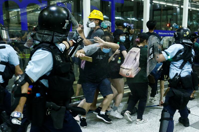 A police officer sprays pepper spray at anti-government protesters during clashes at the airport in Hong Kong. Reuters