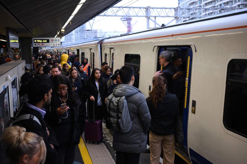 Commuters wait to board a train at Stratford Station in London. AFP