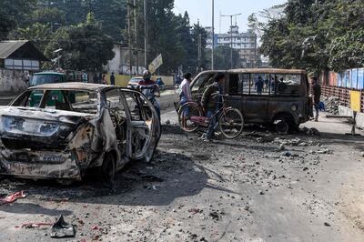 People make their way among the remains of gutted vehicles on a road in Guwahati on December 13, 2019, a day after protests against the government's Citizenship Amendment Bill (CAB) broke out across India's northeastern state of Assam. Internet access has been cut in India's northeastern city of Guwahati after violent protests over a new citizenship law saw two demonstrators shot dead by police, authorities said on December 13. / AFP / Sajjad  HUSSAIN
