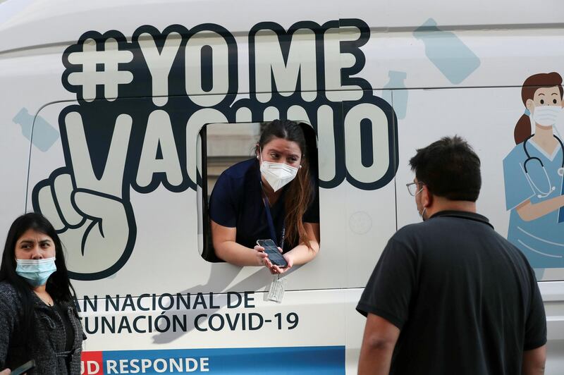 A healthcare worker delivers information as people wait to receive Sinovac's CoronaVac Covid-19 vaccine at a mobile vaccination centre in Chile's capital, Santiago. Reuters