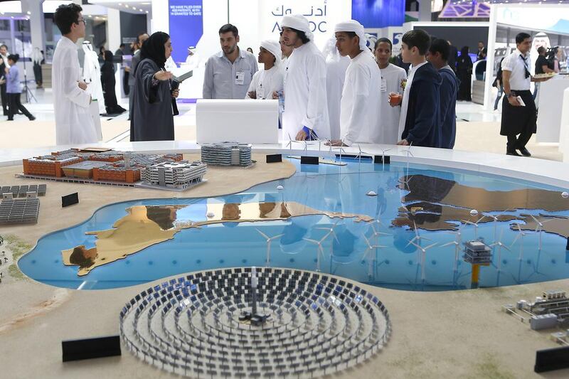 Students look at a scale model featuring solar and wind installations at Masdar’s stand at WFES 2017 yesterday. Ravindranath K / The National
