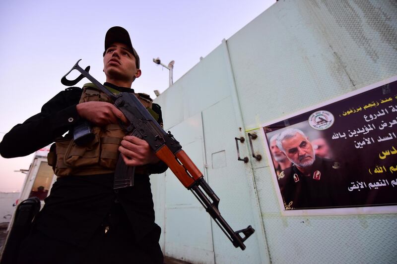 epa08110522 A member of Iran-backed Iraqi Shiite armed group popular mobilization forces stands guard next to placard carrying an obituary notice and the pictures of slain Abu Mahdi al-Muhandis and the Iranian general Qasem Soleimani in front of a military base in Baghdad, Iraq, 07 January 2020.  A US drone strike killed Iraqi militia commander Abu Mahdi al-Muhandis and Qasem Soleimani, the head of Iran's Islamic Revolutionary Guard Corps' elite Quds Force, and the eight others at the Baghdad international airport on 03 January 2020.  EPA/MURTAJA LATEEF