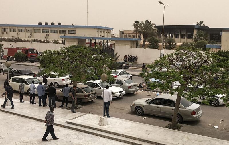 A picture taken on May 2, 2018 shows people gathering outside the Libyan electoral commission headquarters in the capital Tripoli after it was targeted by a suicide attack that killed at least 11 people according to authorities and eyewitnesses.
The internationally backed Government of National Accord (GNA) said it was dealing with "the consequences of the cowardly suicide attack" after the health ministry put the toll at 11 dead and two wounded.  / AFP PHOTO / Mahmud TURKIA