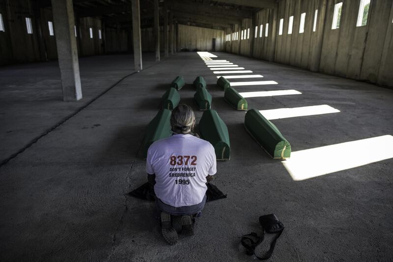 A Bosnian Muslim man prays by coffins of nine victims of the Srebrenica genocide whose remains discovered and identified since July 2019. Getty Images