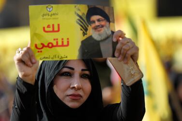 A supporter of Hezbollah leader Sayyed Hassan Nasrallah holds up his portrait with Arabic words that read: "We belong with you," during an election campaign speech in a southern suburb of Beirut in 2018. AP