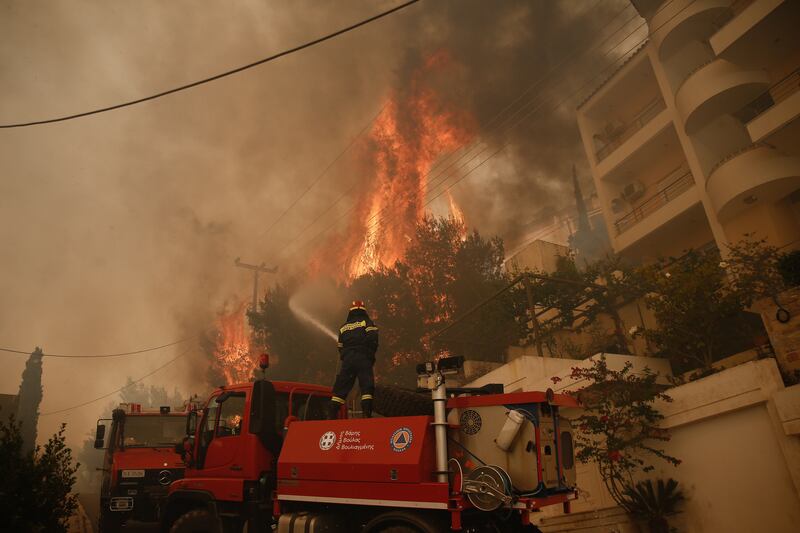 A fireman tries to extinguish flames during a wildfire in the suburb of Voula, south of Athens, Greece.  EPA