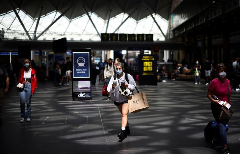 People wearing protective face masks walk through King's Cross Station in London as England approaches its so-called Freedom Day on July 19.