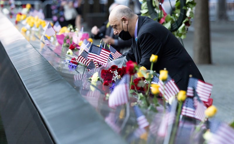 A man places American flags on the South Pool of the 9/11 Memorial during a ceremony marking the 20th anniversary of the 11 September 2001 terrorist attacks in New York, New York, USA,.  EPA