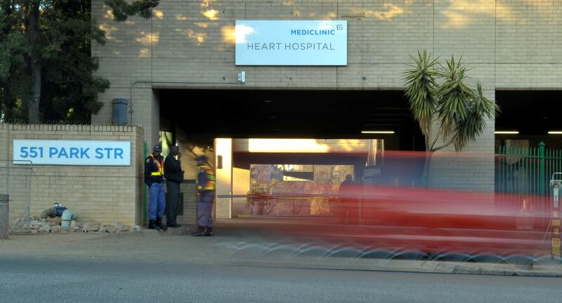 Sercurity stands outside the Mediclinic heart hospital in Pretoria on June 25, 2013, where former President Nelson Mandela spent  a second night in critical condition.  People on thier way to work. South African President Jacob Zuma, in a televised address to an anxious nation, said on June 24 that "former president Mandela remains in a critical condition in hospital." Mandela, the hero of black South Africans' battle for freedom during 27 years in apartheid jails, was rushed to hospital on June 8 with a recurring lung infection.       AFP PHOTO / ALEXANDER JOE / AFP PHOTO / ALEXANDER JOE