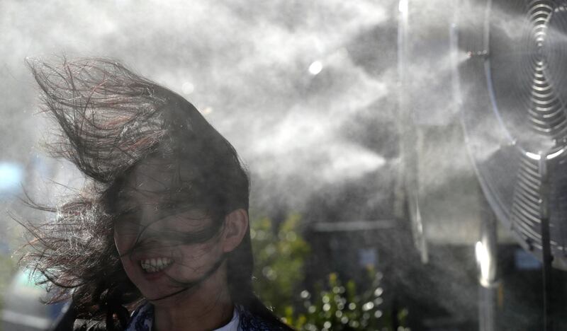 A fan cools down under a spray of water. Temperatures are expected to soar to up to 38 degrees Celcius during the first week of the event. Mark Cristino / EPA