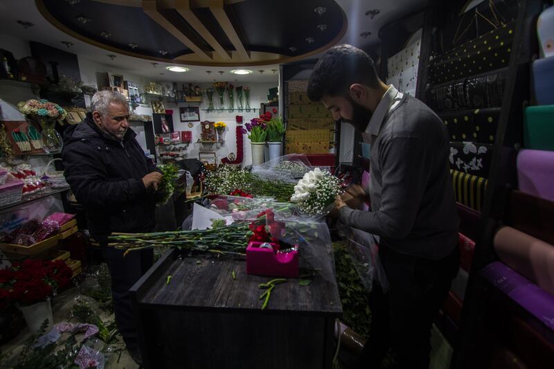 Khaled, the owner of a flower shop, and his father wrap flowers and make bouquets of different colours in preparation. Khaled said the war has taken joy from the country, but people have to continue their lives.