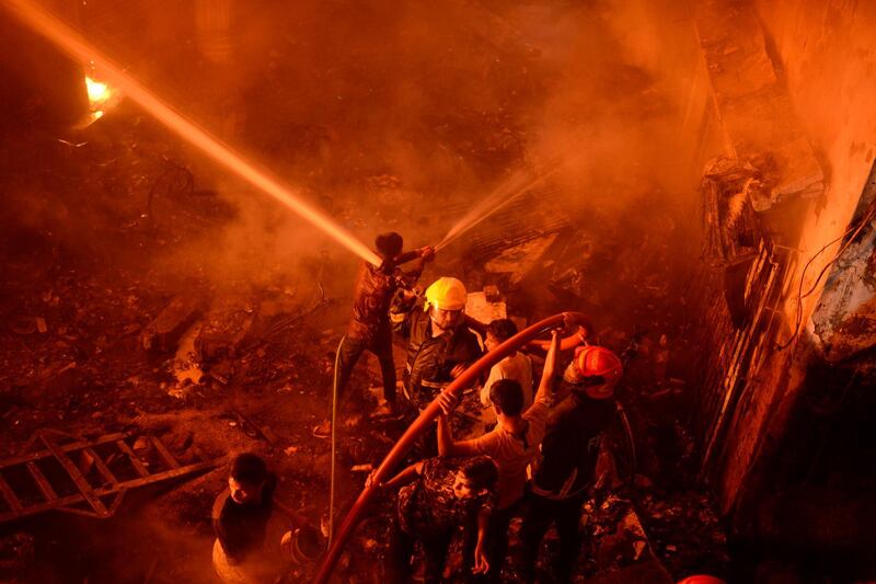 In this Wednesday, Feb. 20, 2019, photo, firefighters try to douse flames in Dhaka, Bangladesh. A devastating fire raced through at least five buildings in an old part of Bangladesh's capital and killed scores of people. (AP Photo/Mahmud Hossain Opu)