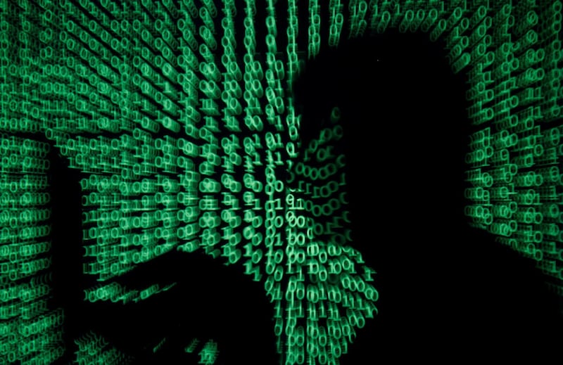 FILE PHOTO: A man holds a laptop computer as cyber code is projected on him in this illustration picture taken on May 13, 2017. REUTERS/Kacper Pempel/Illustration/File Photo