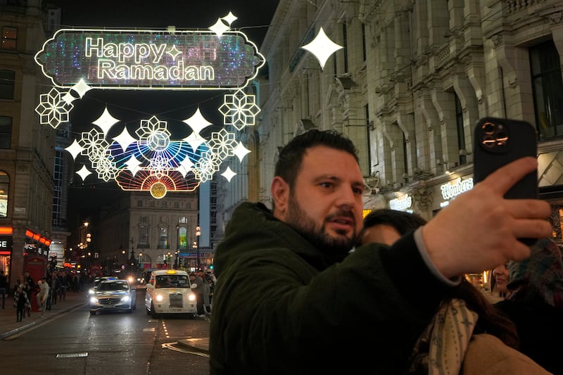 A man takes a selfie in front of the Ramadan lights at Piccadilly Circus in central London. AP