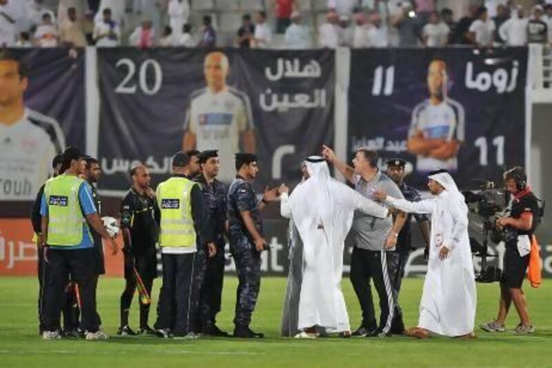 Al Ain manager Cosmin Olaroiu, in the grey shirt, has to be restrained by team officials and security while clashing with referees at the conclusion of his team's 2-1 loss to Al Ahli. Al Ittihad