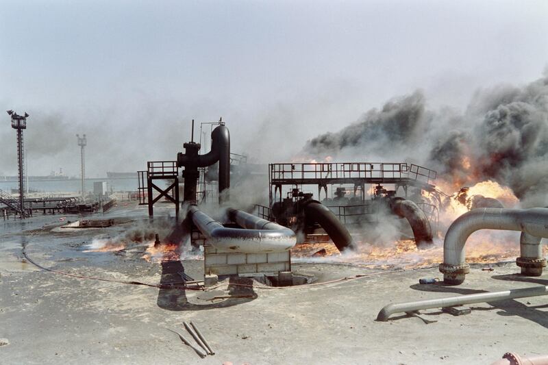 An oil refinery, set alight by Iraqi troops, continues to burn and plunges area into pitch black darkness in the south of Kuwait city on March 1, 1991. Iraqi troops set hundreds of oil wells alight during the war. (Photo by Vincent AMALVY / AFP)