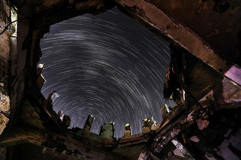 This long-exposure picture taken shows a view of star trails in the sky through a hole left by a collapsed dome of a destroyed mosque in the town of Binnish in Syria's northwestern Idlib province.  AFP