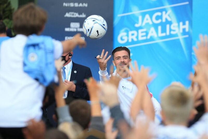 Jack Grealish throws a ball to Manchester City fans outside the Etihad Stadium.