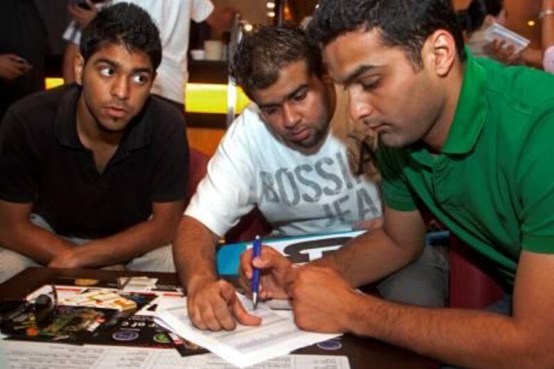 Dubai, March 21, 2011 - Members of team Chill Meena from left Zoheb Mustafa watches as Sagar Ankolekar helps Prithvi Adnani select cricket players their team, one of 16 participating in the auction, will bid on during a cricket World Cup fantasy auction in the Sports Lounge of the Citymax Hotel in Bur Dubai, Dubai March 21, 2011. (Jeff Topping/The National)