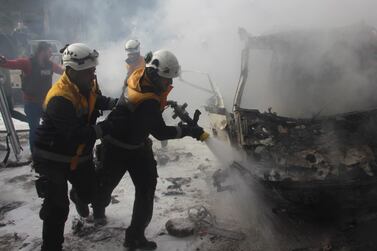 Rescue workers extinguish a burning car that was set alight by the airstrike. AP