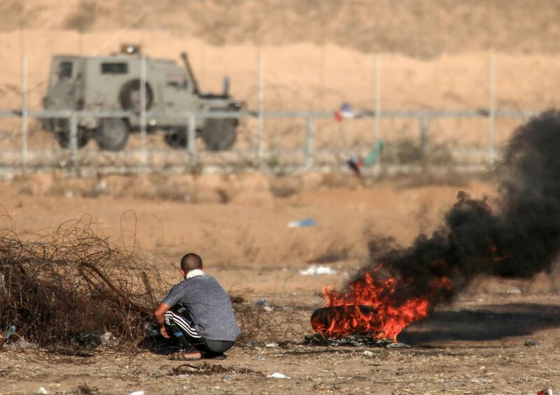 A Palestinian protester takes cover from an Israeli vehicle during clashes across the border following a demonstration along the fence east of Khan Yunis in the southern Gaza strip.  AFP