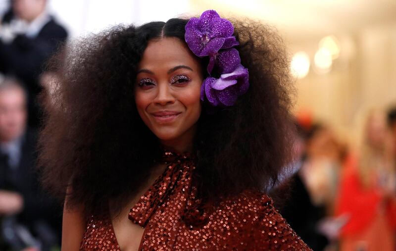 Actress Zoe Saldana's brushed-out curls were accentuated with purple blooms tucked behind one ear, while a glittery overlay on her eyelids echoed her twinkling gown. Reuters