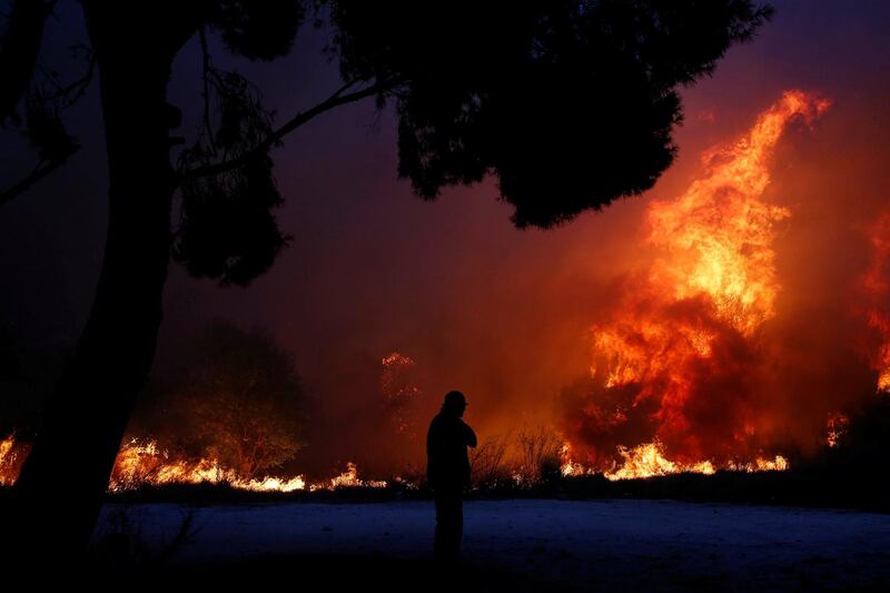 A man looks at the flames as a wildfire burns in the town of Rafina, near Athens, Greece.  Reuters