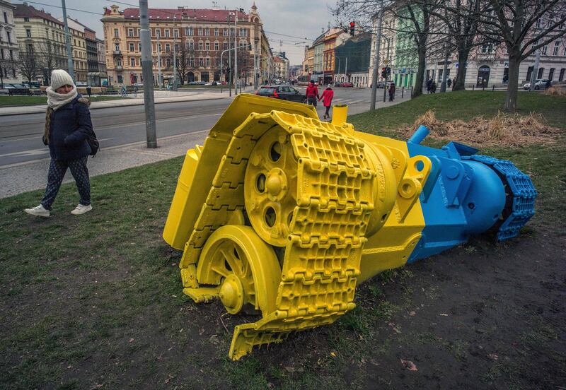 A woman walks past a tank sculpture painted in the colours of the Ukrainian flag by Czech artist David Cerny in Prague. AFP