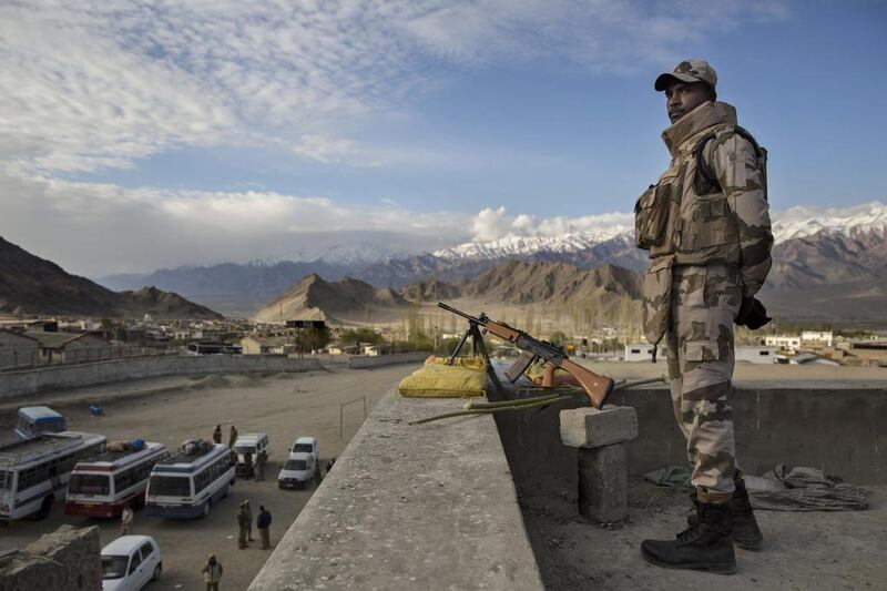 Security force soldier stands guard on a rooftop at a central collection point for distribution of voting machines for polling stations.