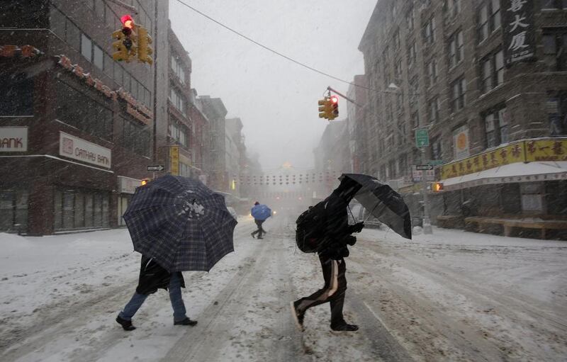 Pedestrians use umbrellas as they walk through falling snow in the Chinatown neighbourhood of New York on Thursday as snow and sleet fell on the East Coast from North Carolina to New England. Mark Lennihan / AP Photo