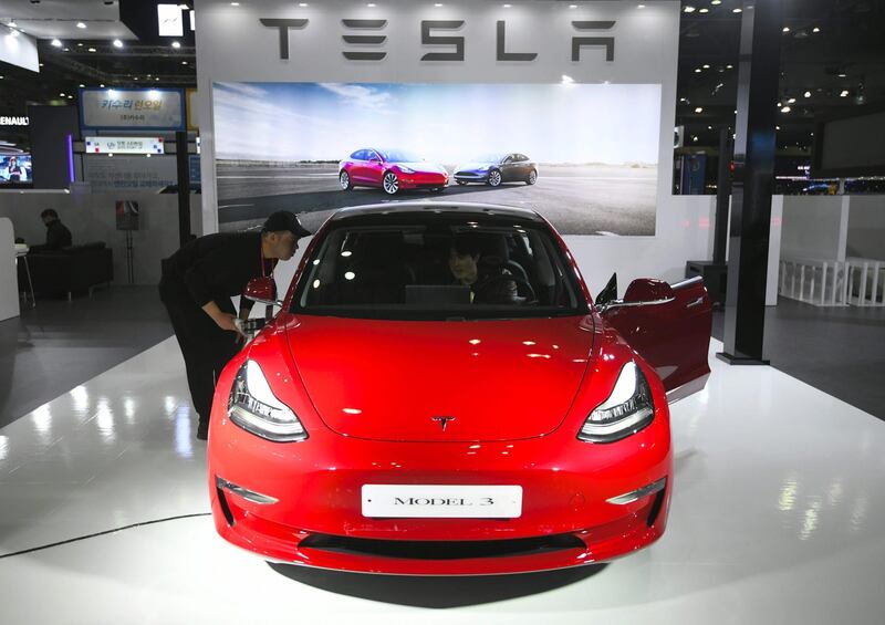 Visitors look at a Tesla Model 3 at the show. Jung Yeon-Je / AFP