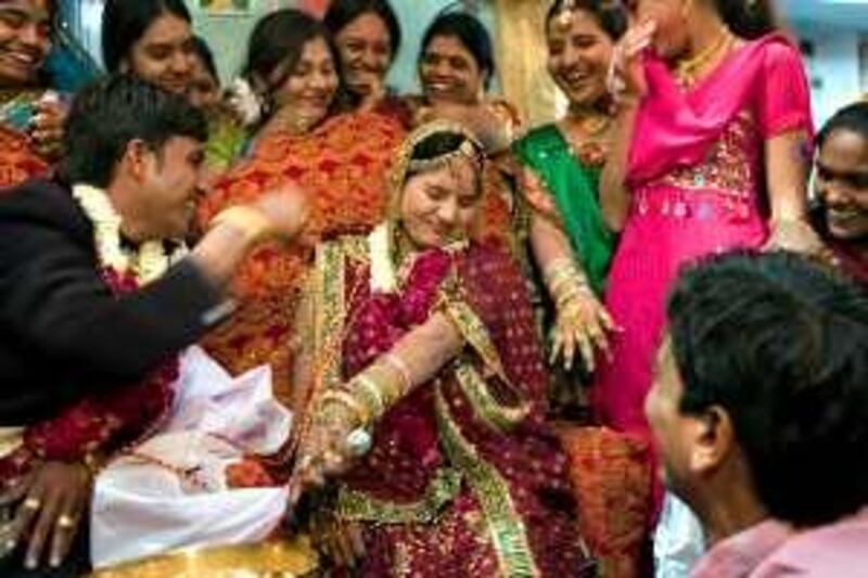 An Indian Bharwad (shepherd) bride (C) reacts as her husband prepares to feed her during a ritual at a wedding ceremony in Ahmedabad on February 15, 2009. Fifty-one Bharwad couples tied the knot in a communal marriage organised by the "Nava Wadaj Gopalak Samaj" in Ahmedabad. AFP PHOTO/ Sam PANTHAKY