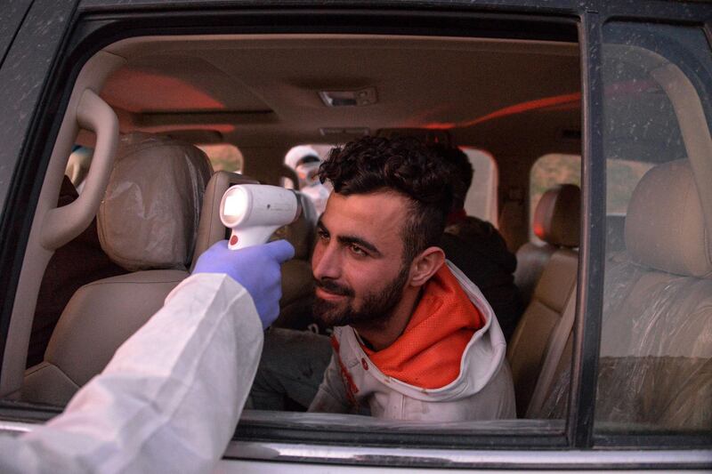 An Iraqi health ministry worker scans the body temperature of a passenger in an incoming vehicle in Iraq's northern city of Mosul.   AFP