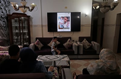 The family of nine months old Palestinian baby Omar Yagi look at a TV screen displaying pictures of him in Gaza City on June 22, 2020. Baby Omar Yaghi was eight months old when he died, unable to travel from Gaza to Israel for life-saving heart surgery after Palestinian officials cut coordination. Yaghi was born with complex heart problems and he started treatment at Israel's Sheba Medical Center when he was just one month old. Having been unable to return for the surgery, Yaghi suffered heart failure on June 17 and was resuscitated at a Gaza hospital. / AFP / MOHAMMED ABED
